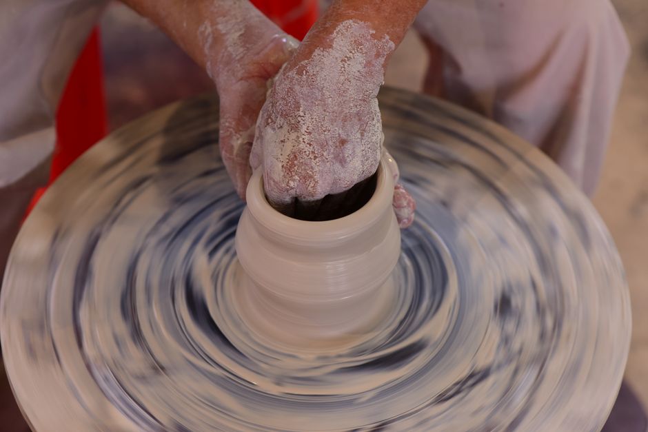 Hands expertly shaping clay on a pottery wheel, illustrating the art of ceramic creation.